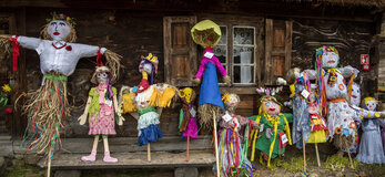 słomiane kukły ustawione pod drewnianą chatą